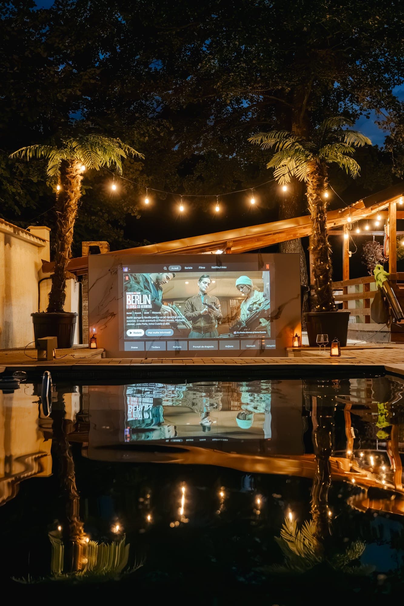 Cinema în aer liber seara, cu ecranul reflectat în piscină, la Villa Palm